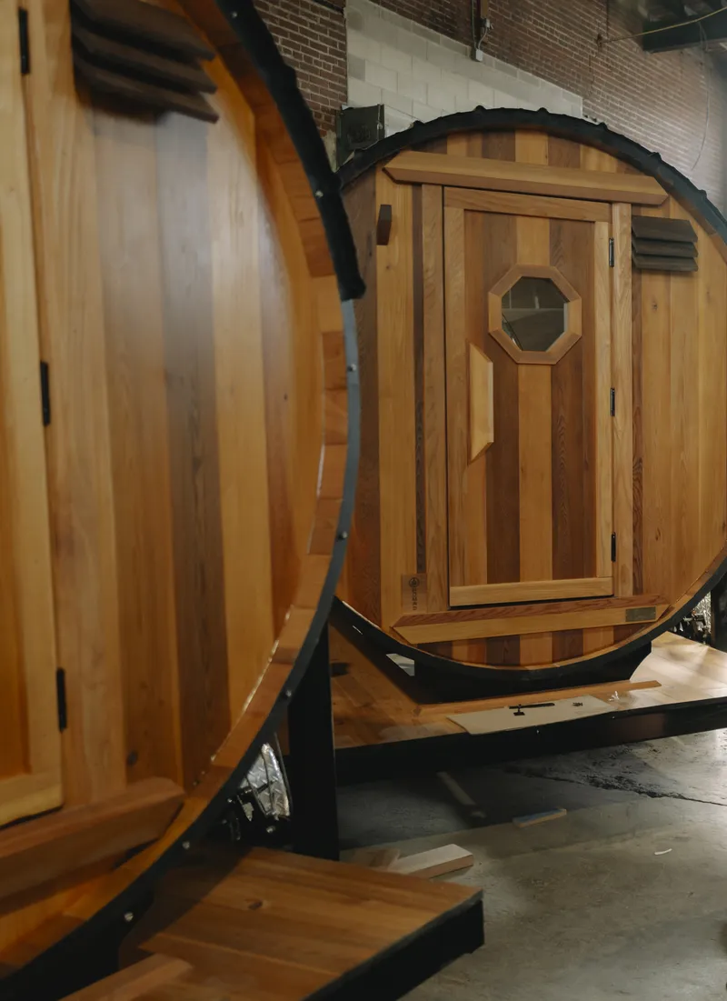 Barrel sauna front wall showing natural cedar wood grain gradients and standard wood pull handle